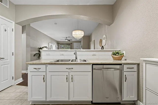 a sink with a granite countertop cabinets and a view of living room