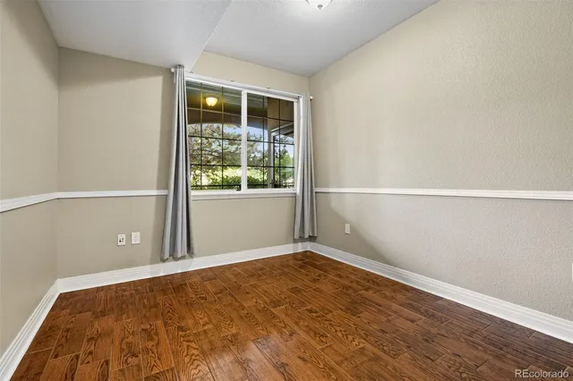 a view of an empty room with wooden floor and windows