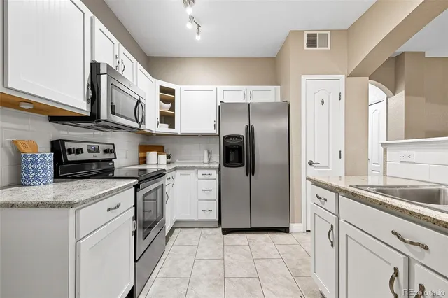 a kitchen with stainless steel appliances granite countertop a refrigerator and a sink