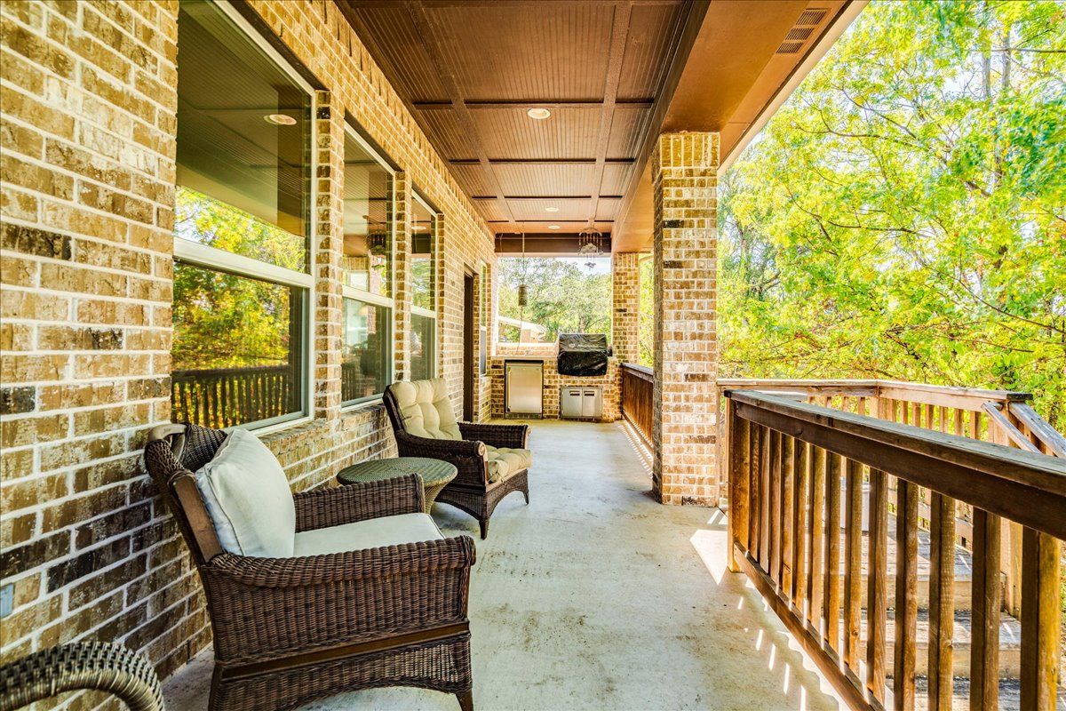 12909 Medina River Way Austin, TX 78732 - Photo 33 of 36 An inviting covered porch features classic brick columns, a coffered ceiling, and wooden railings, perfect for entertaining.