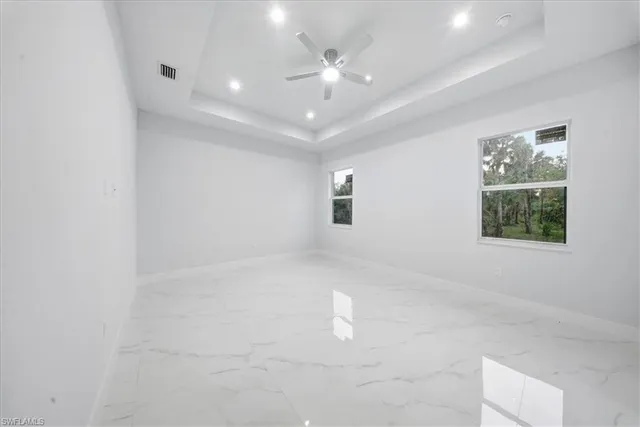 an empty room with windows and ceiling fan