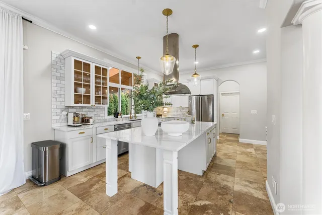 a kitchen with stainless steel appliances kitchen island granite countertop a sink and a refrigerator