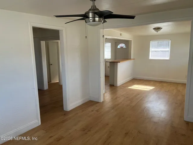 an empty room with wooden floor cabinet and windows