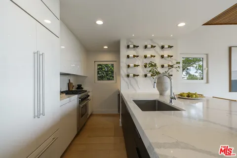 a large white kitchen with stainless steel appliances a sink a stove and a refrigerator