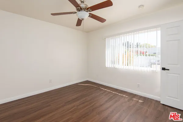 an empty room with wooden floor fan and windows
