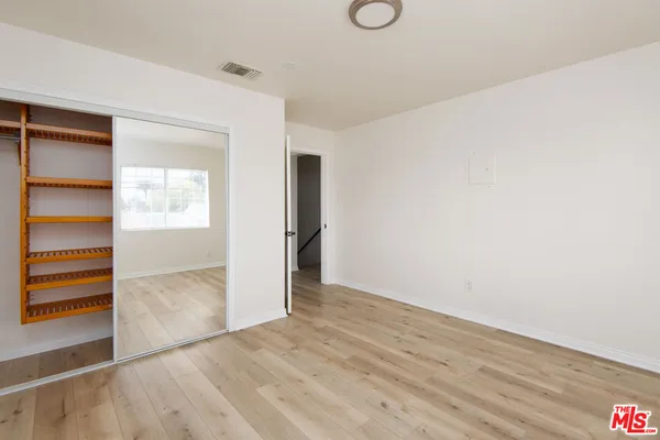 an empty room with wooden floor closet and windows