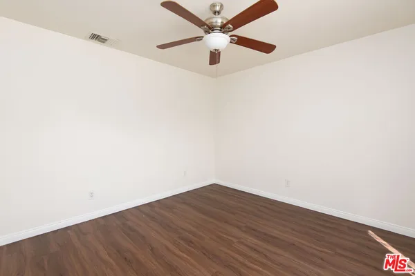 an empty room with wooden floor and a ceiling fan