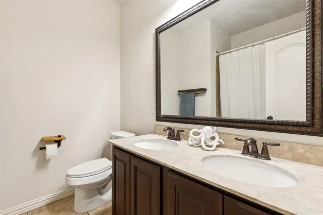 a bathroom with a granite countertop sink toilet and mirror