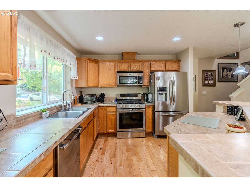37702 Hamilton Ridge Drive Sandy, OR 97055 - Photo 13 of 44 a kitchen with kitchen island granite countertop a stove top oven a sink dishwasher a refrigerator and a dining table with wooden floor