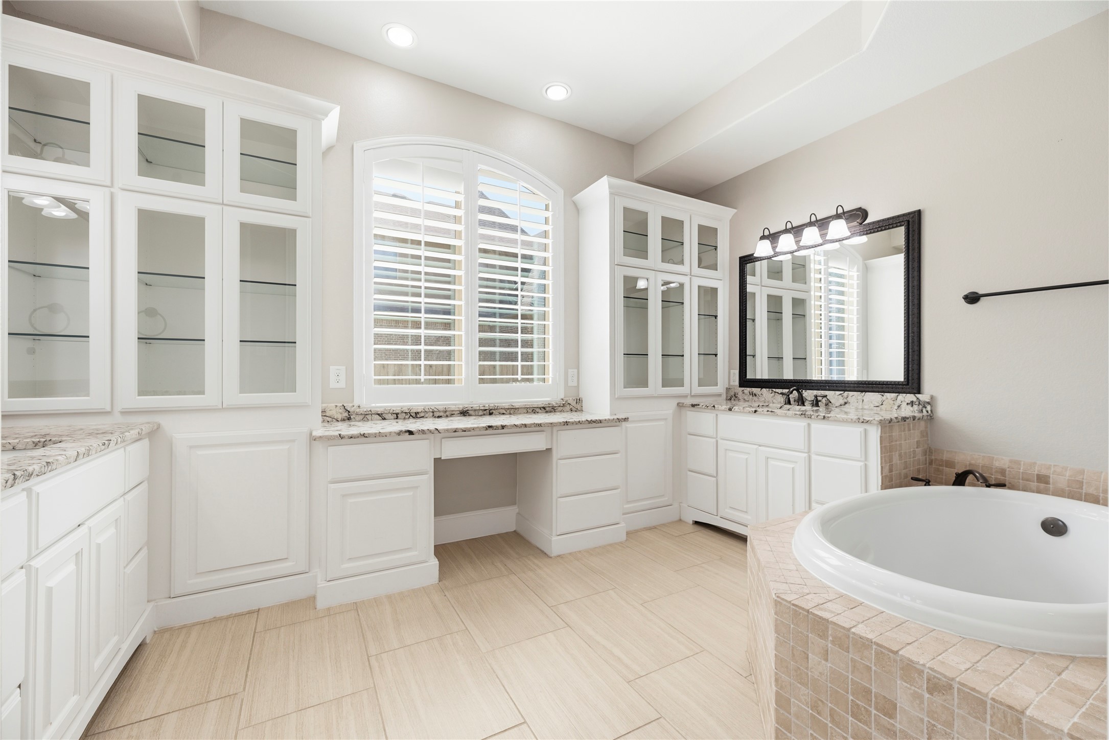 28226 South Firethorne Road Katy, TX 77494 - Photo 16 of 39 The primary bathroom features double sinks with sleek granite countertops and expansive custom-built cabinetry, including glass-front display towers for a refined, organized aesthetic.