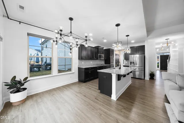 a large kitchen with stainless steel appliances kitchen island a large counter top and wooden floors