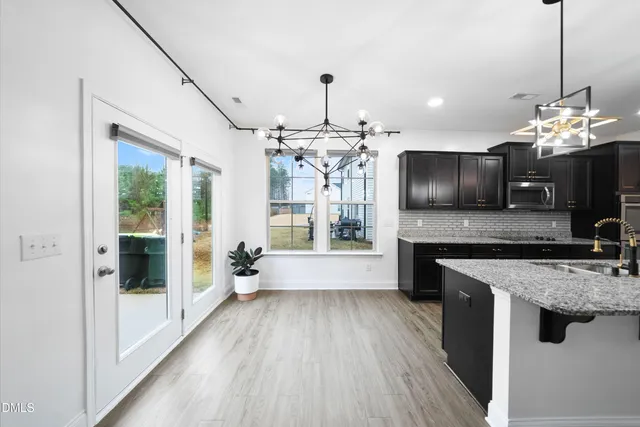 a kitchen with kitchen island granite countertop a stove top oven a sink dishwasher a dining table and chairs with wooden floor