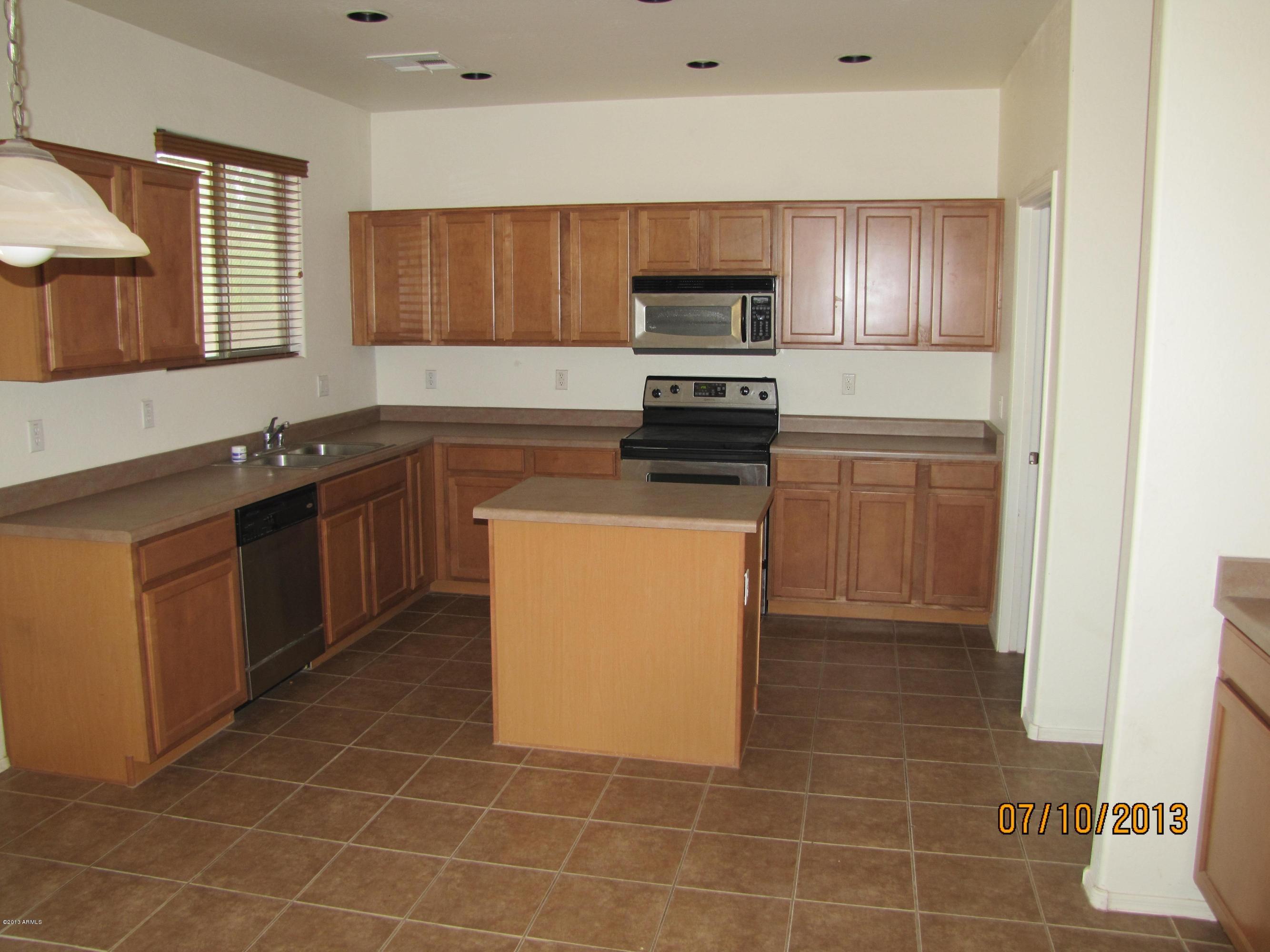 44134 Roth Road Maricopa, AZ 85138 - Photo 4 of 13 a kitchen with stainless steel appliances a sink a stove a microwave a counter top space and cabinets