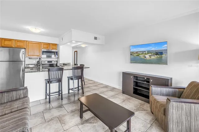a living room with furniture a flat screen tv and kitchen view
