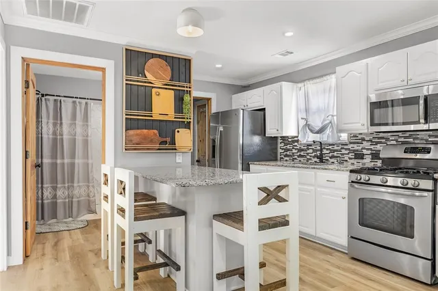 a kitchen with stainless steel appliances granite countertop a stove top oven a sink dishwasher and a refrigerator with wooden floor