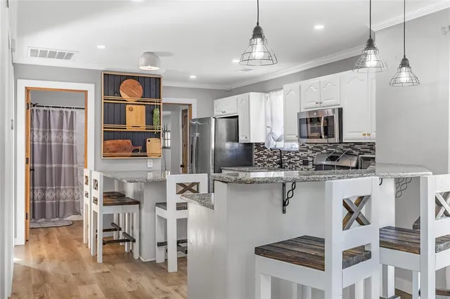 a view of kitchen with stainless steel appliances kitchen island granite countertop refrigerator and cabinets