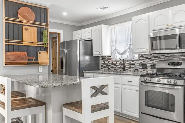 a kitchen with stainless steel appliances a stove a microwave sink and cabinets