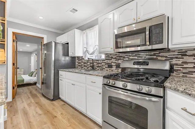 a kitchen with granite countertop sink stainless steel appliances and white cabinets