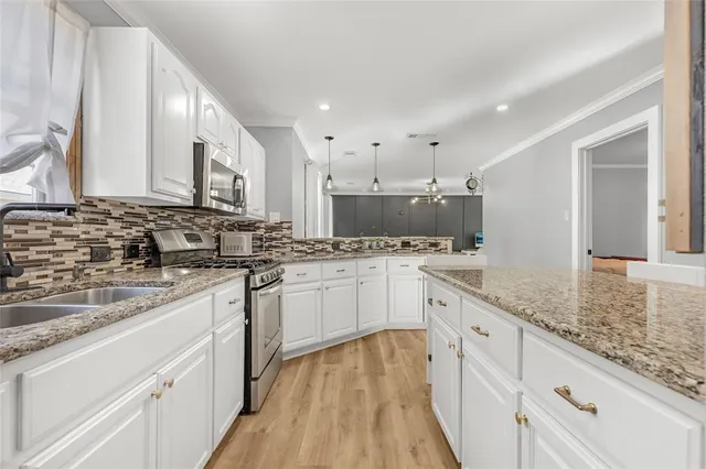 a kitchen with kitchen island granite countertop a sink a stove and cabinets