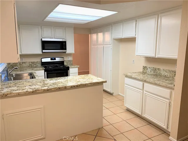 a kitchen with granite countertop white cabinets and stainless steel appliances