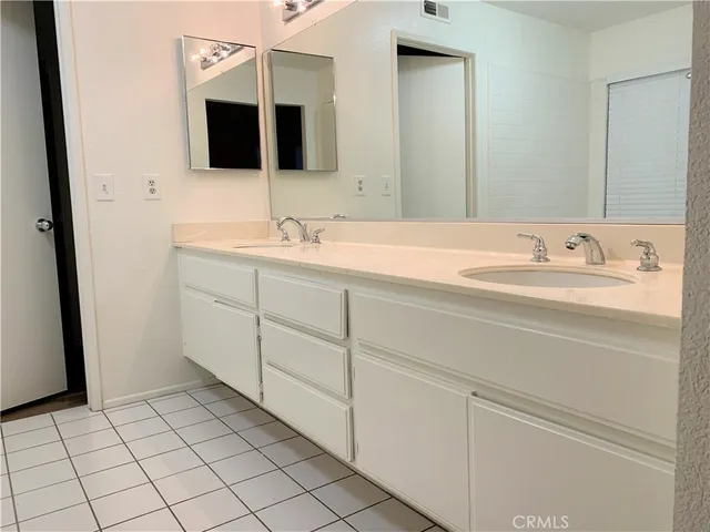 a spacious bathroom with a double vanity sink and mirror