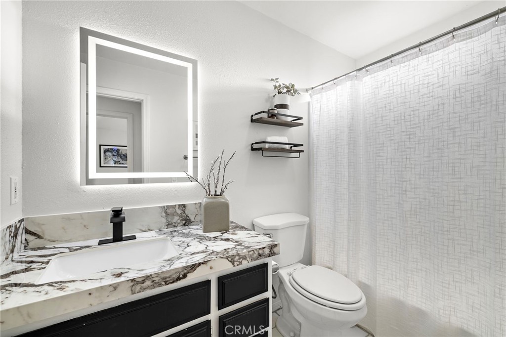 168 23rd Street, Unit D Costa Mesa, CA 92627 - Photo 19 of 26 a bathroom with a granite countertop sink toilet and mirror