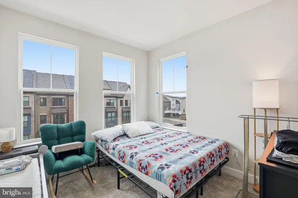 a bedroom with a bed a couch and a potted plant on the dresser