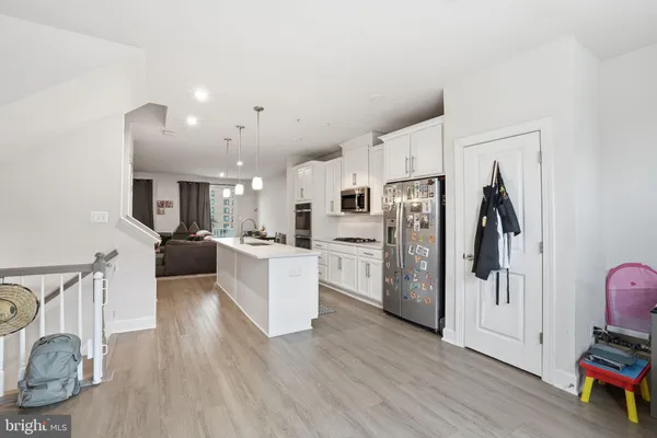 a large white kitchen with stainless steel appliances lots of counter space and wooden floor