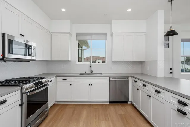 a kitchen with stainless steel appliances white cabinets a sink and wooden floor
