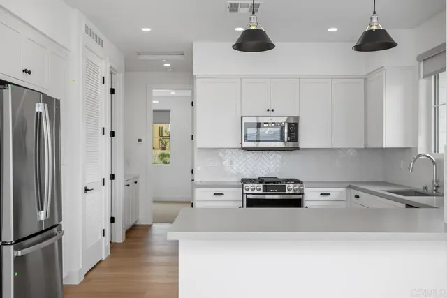 a kitchen with stainless steel appliances a refrigerator a sink and white cabinets