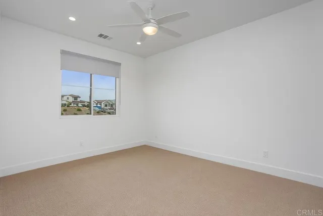 an empty room with a fan & a window