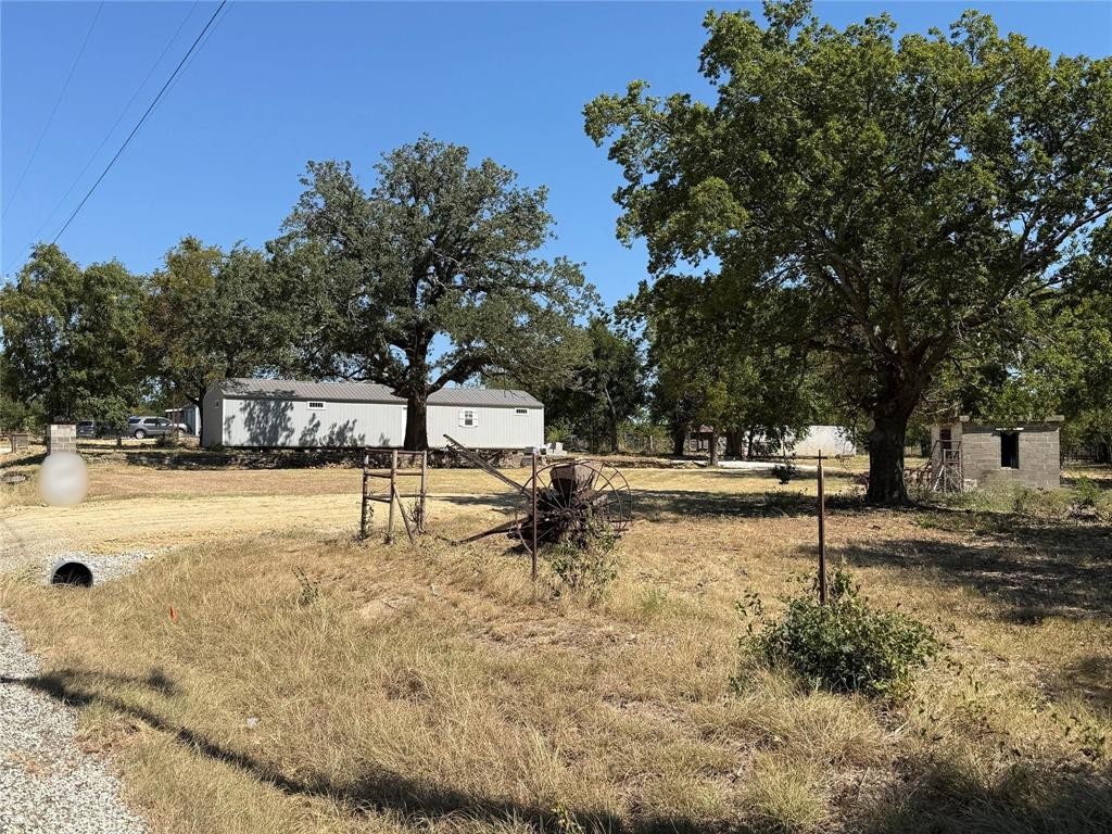 803 Billings Road Tolar, TX 76476 - Photo 2 of 7 Expansive lot featuring mature trees, a detached structure with siding, and a separate masonry outbuilding
