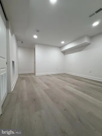 an empty room with wooden floor and natural light