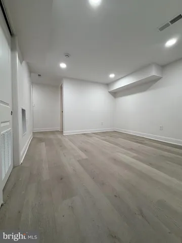 an empty room with wooden floor and natural light
