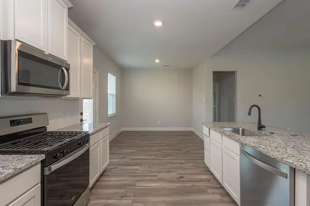 a large kitchen with stainless steel appliances a large counter top and a refrigerator