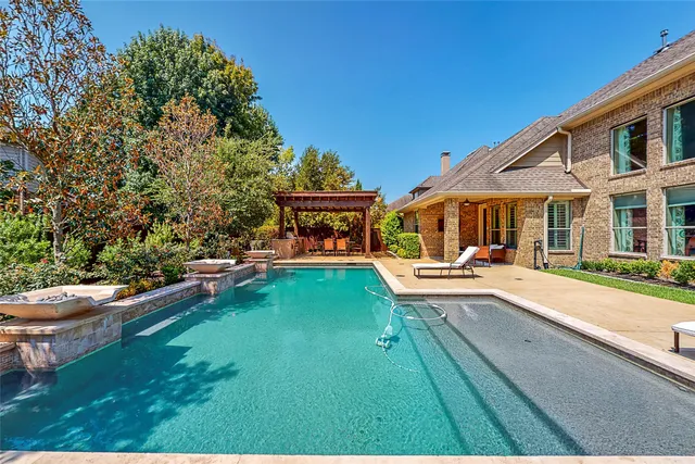 a view of swimming pool with lawn chairs and plants