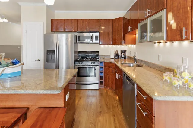 a kitchen with stainless steel appliances granite countertop a sink a stove and a wooden cabinets