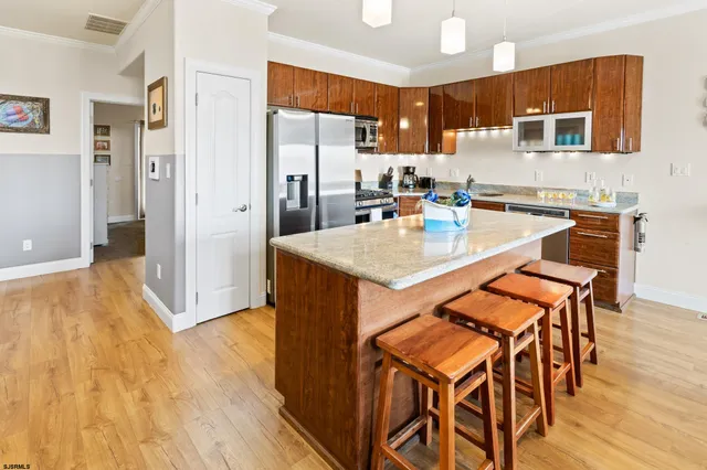 a kitchen with stainless steel appliances granite countertop a stove top oven a sink a dining table and chairs with wooden floor