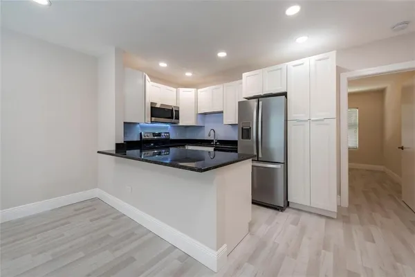 a kitchen with stainless steel appliances granite countertop a refrigerator a stove a sink and a microwave oven with wooden floor