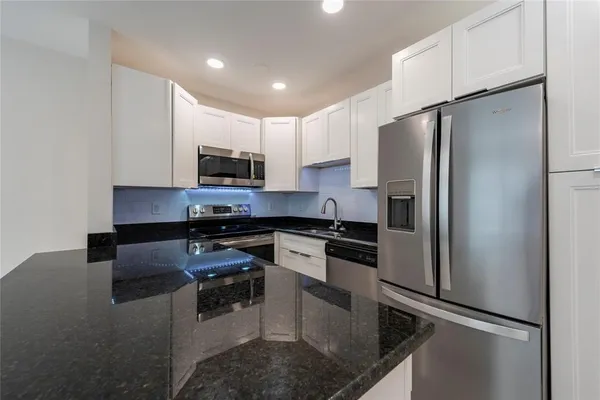 a kitchen with stainless steel appliances granite countertop a refrigerator a stove a microwave oven a sink and dishwasher