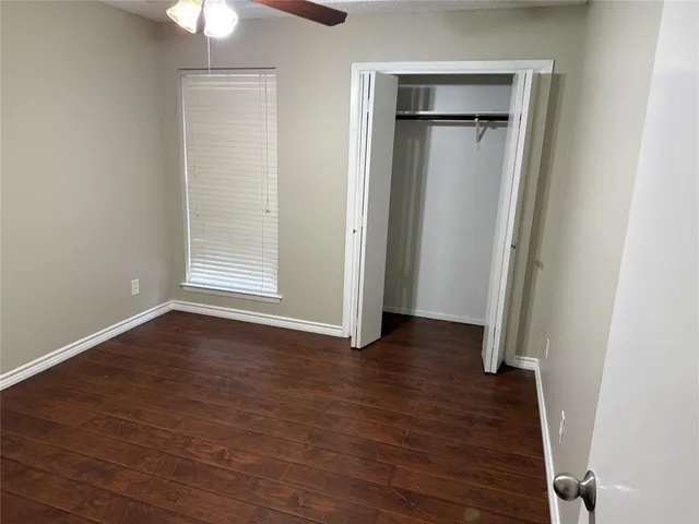 an empty room with wooden floor closet and windows