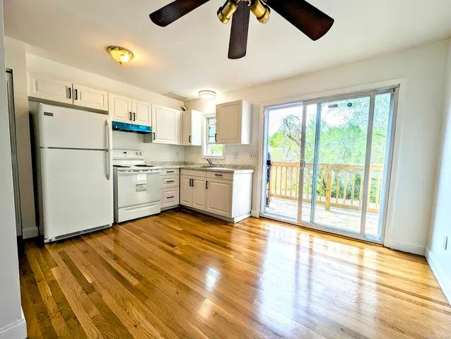 a kitchen with a refrigerator a stove cabinets and wooden floor
