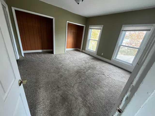 a view of an empty room with windows and closet