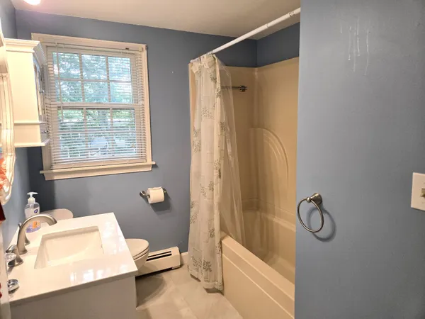 a bathroom with a granite countertop bathtub shower sink vanity and a toilet