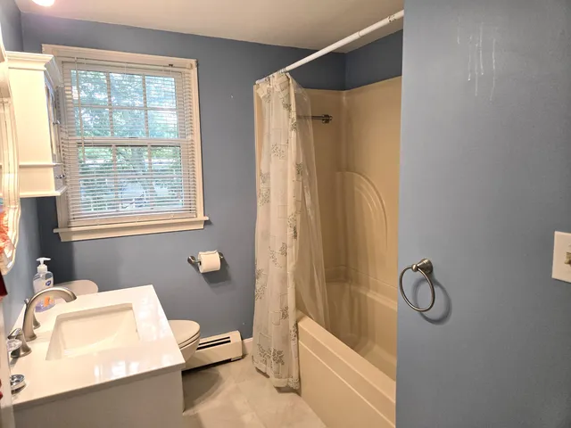 a bathroom with a granite countertop bathtub shower sink vanity and a toilet
