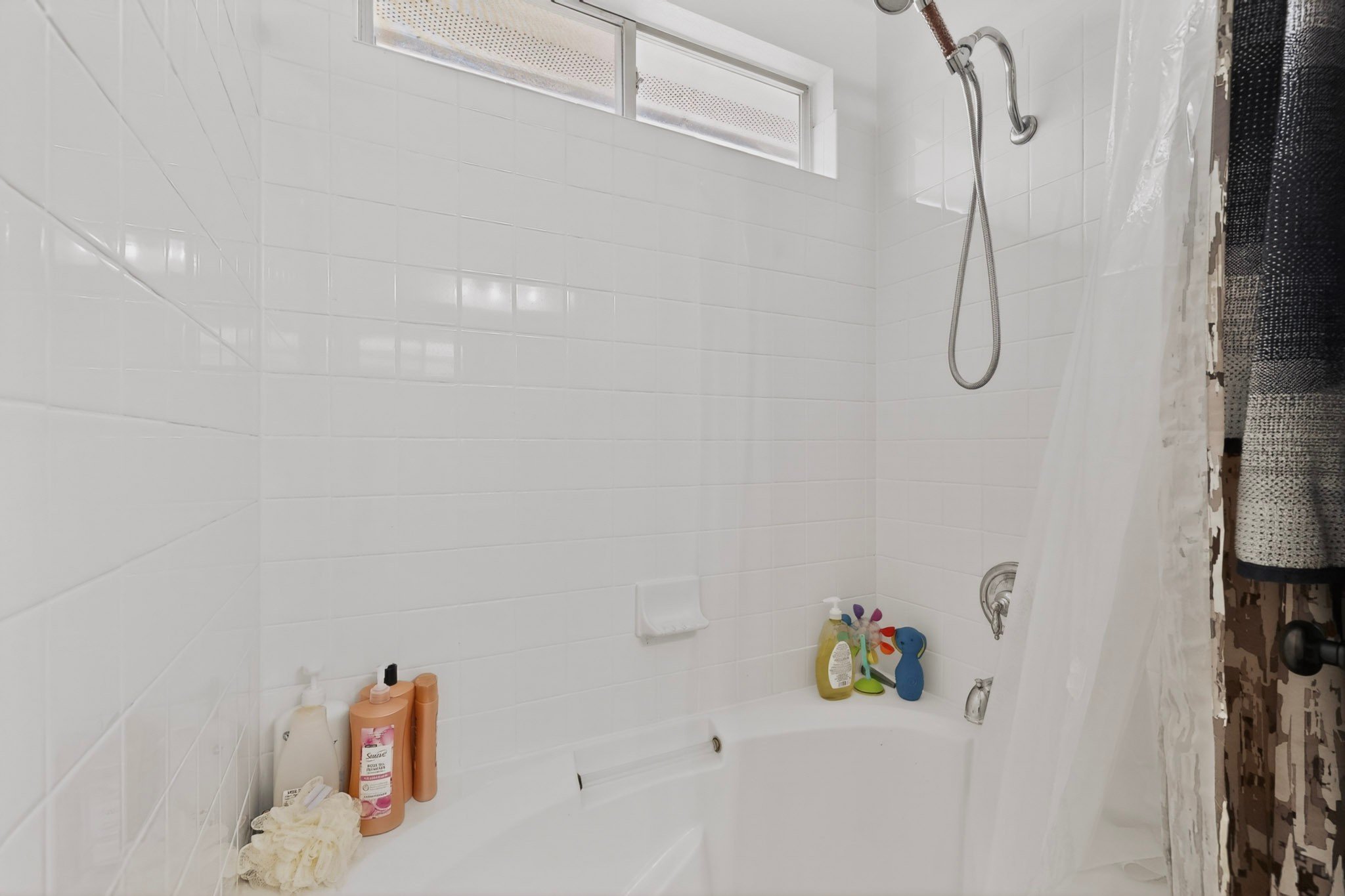 15104 Mimebark Way Austin, TX 78724 - Photo 23 of 38 White subway tile enclosure featuring a built-in bathtub, a window, and a wall-mounted shower fixture