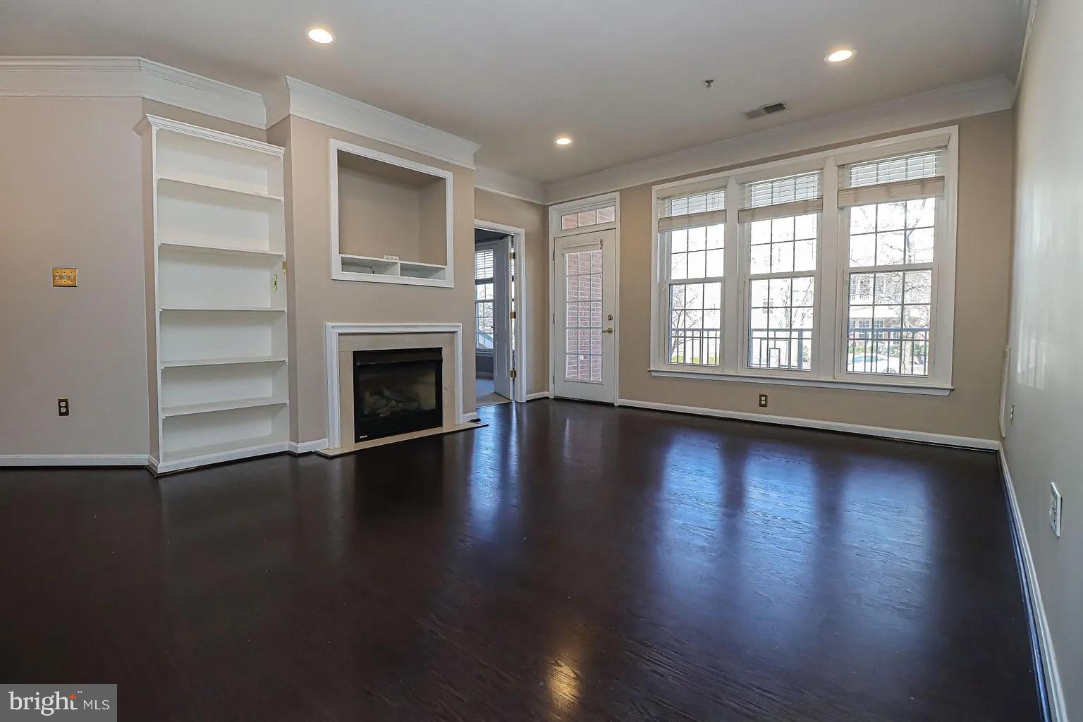 an empty room with wooden floor fireplace and windows