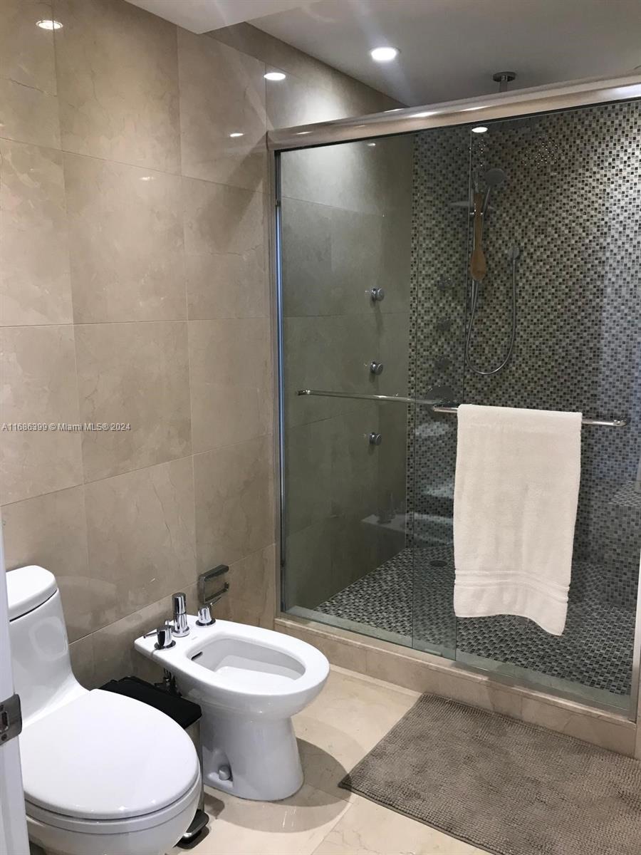 1865 Brickell Avenue, Unit APH6 Miami, FL 33129 - Photo 19 of 24 a white toilet sitting next to a bathroom sink and a shower