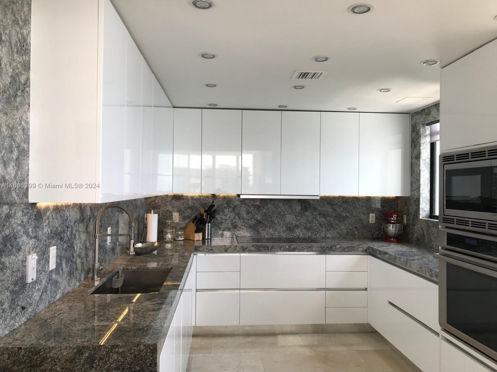1865 Brickell Avenue, Unit APH6 Miami, FL 33129 - Photo 10 of 24 a kitchen with granite countertop a sink a stove and cabinets