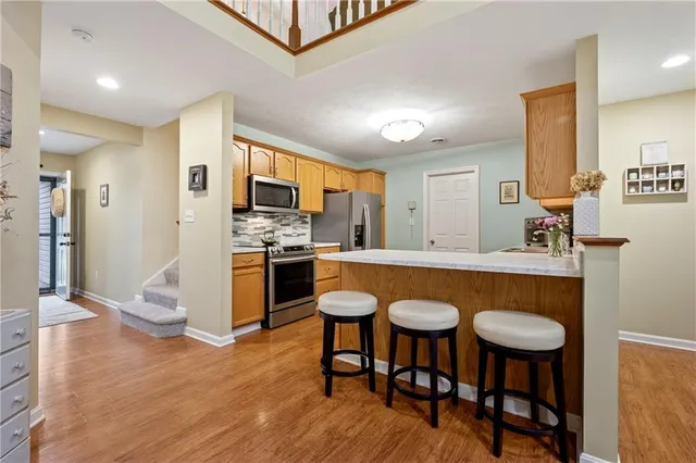 a kitchen with stainless steel appliances granite countertop a dining table chairs refrigerator and sink